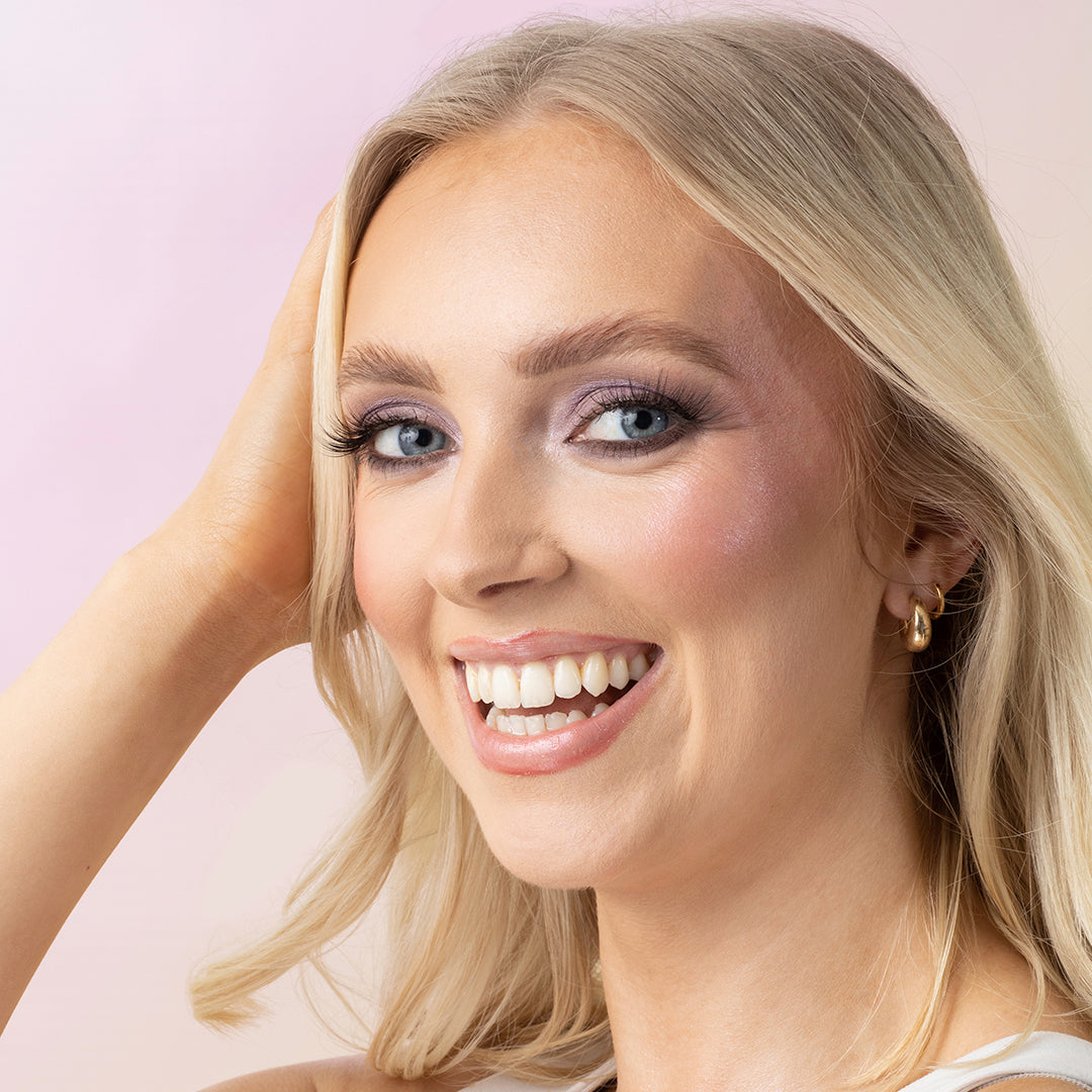 a woman smiling with her hand on her head