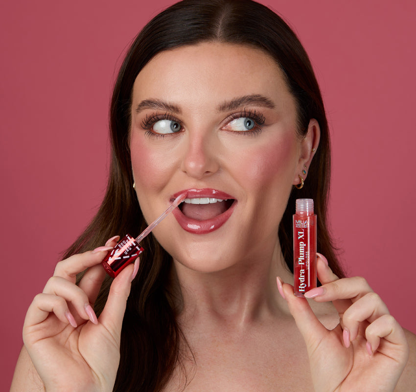 a woman holding a small tube of lip gloss