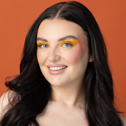 a woman with long black hair and yellow makeup
